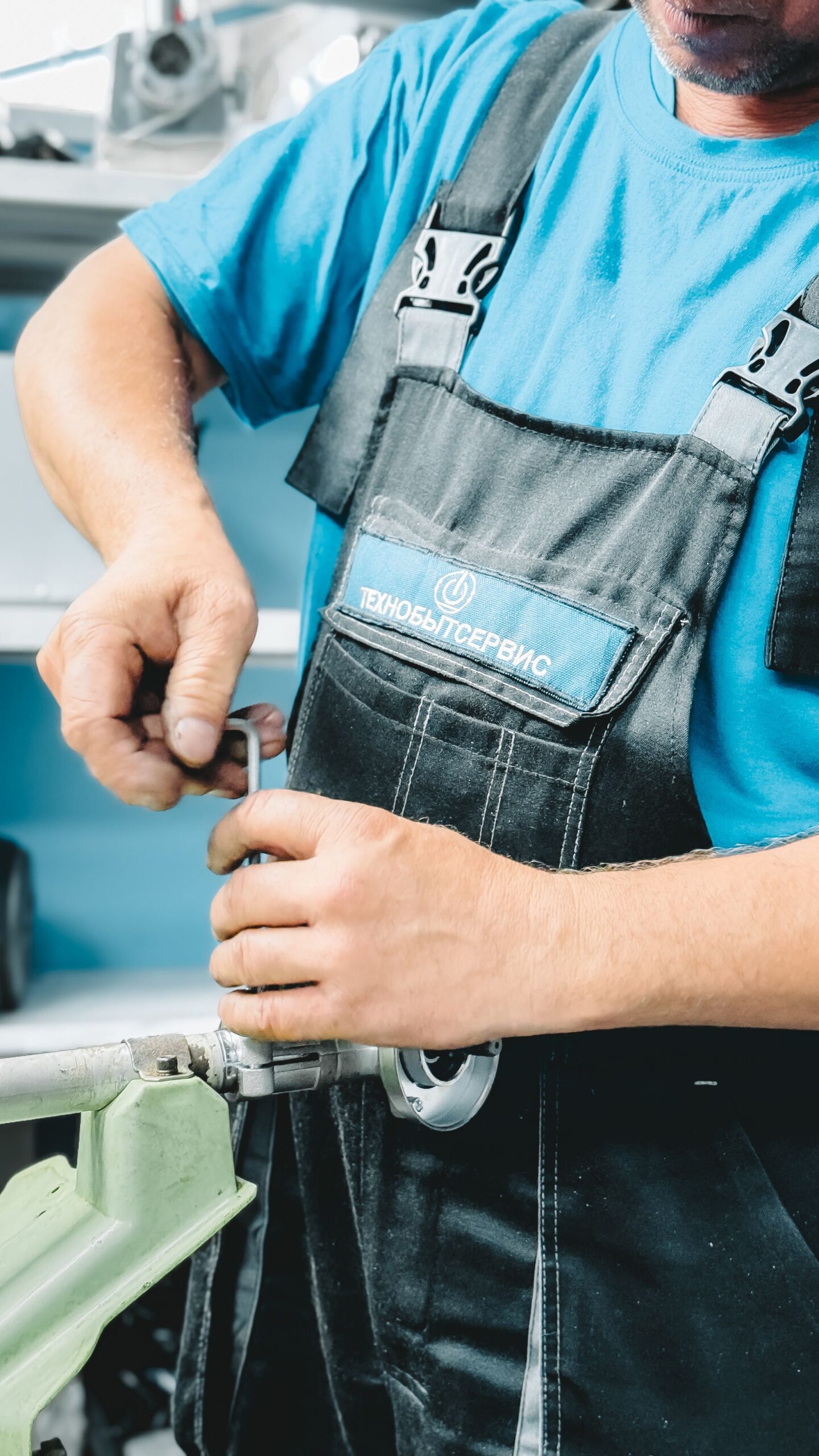 Plumber in blue uniform repairing a pipe with a wrench